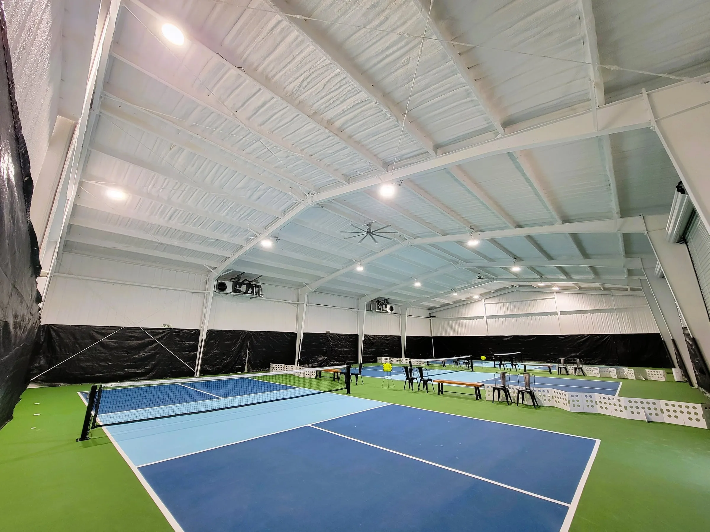Three indoor courts under the high white roof at Pickle Pit Stop